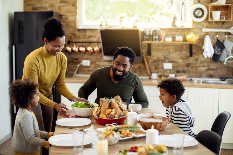 Happy African American parents and their kids having a meal for the holiday season. 