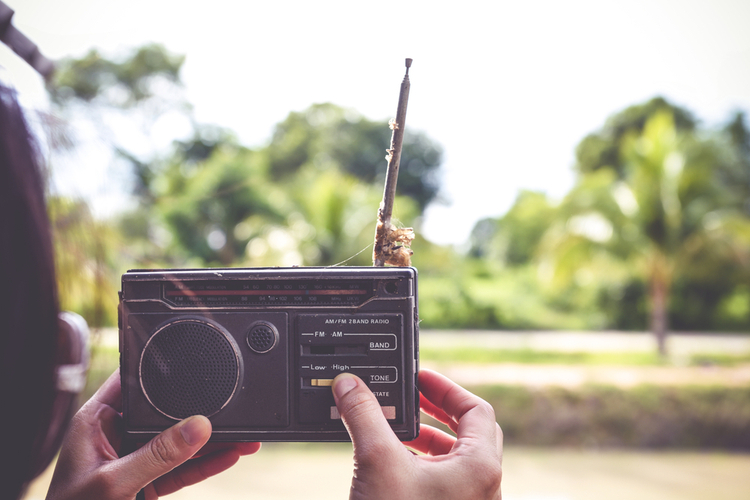 Woman listening to a battery powered radio for news.