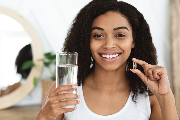 Woman holding a glass of water and nature plus citrimax garcinia cambogia supplement.