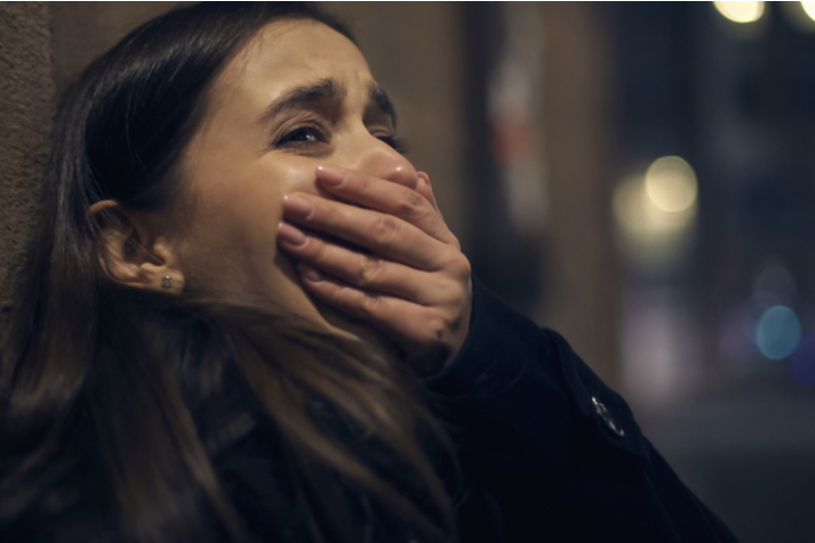 Shocked robber victim crying at night street, panic attack, traumatic experience.