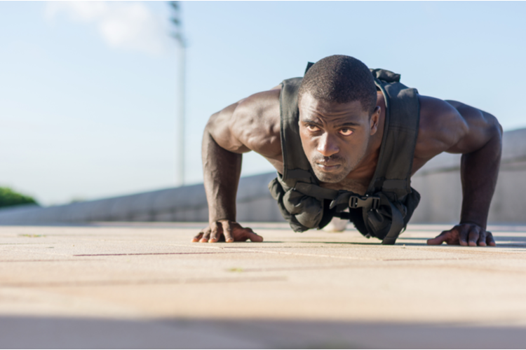 Muscular man doing push-ups with a full of weight vest