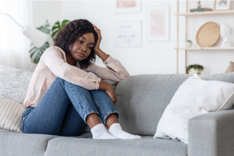 A woman sitting in her couch feeling lonely. How to cope with anxiety?