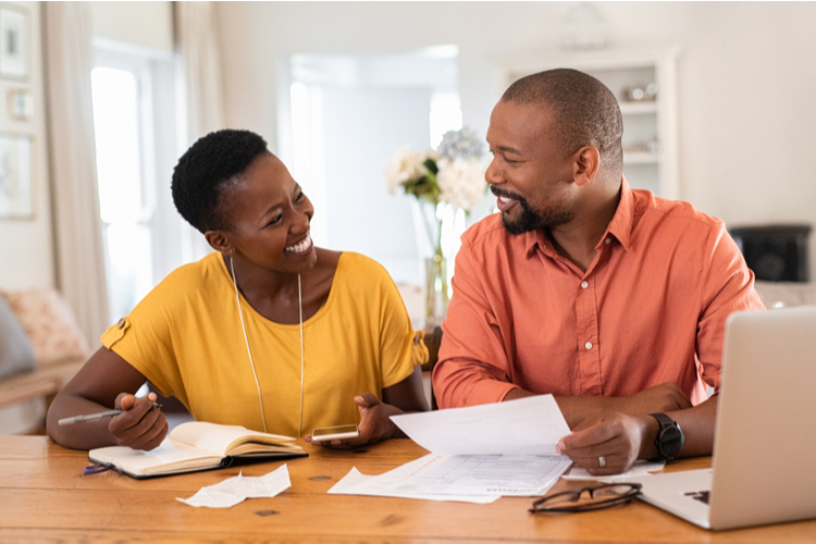 Mature couple sitting and managing expenses at home.