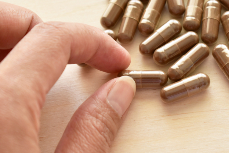 FreshCap Mushroom Review: Lingzhi Mushroom or Reishi Mushroom Supplement Capsules. Traditional Chinese Medicine. Selective Focus at The Capsules in Hand