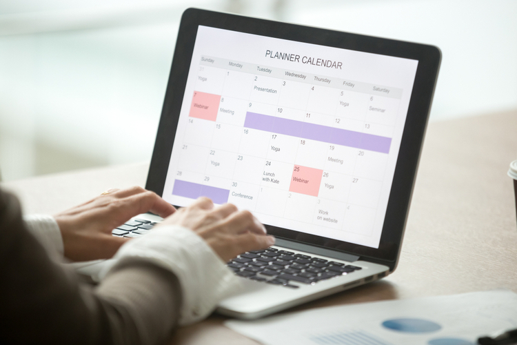 Businesswoman planning day using digital planner or calendar software application on laptop screen.