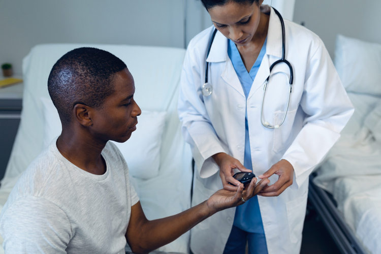 Side View of Mixed Race Female Doctor Taking African American Patients Blood Sample With Lancet Pen in The Ward at Hospital