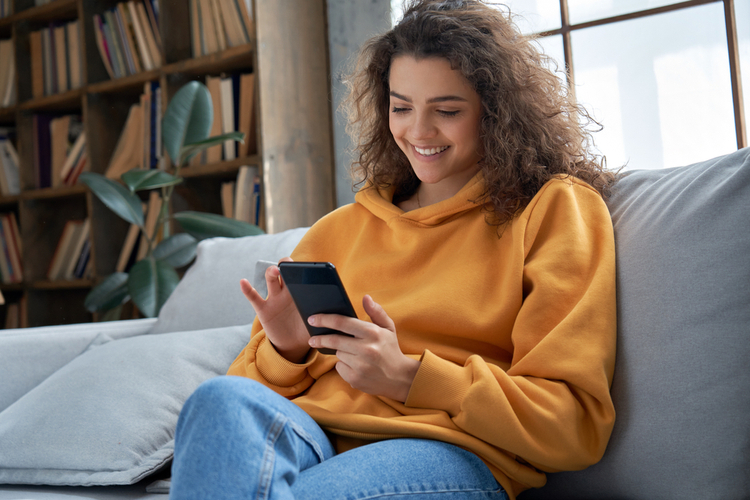 Teen girl checking mental health apps holding a smartphone.