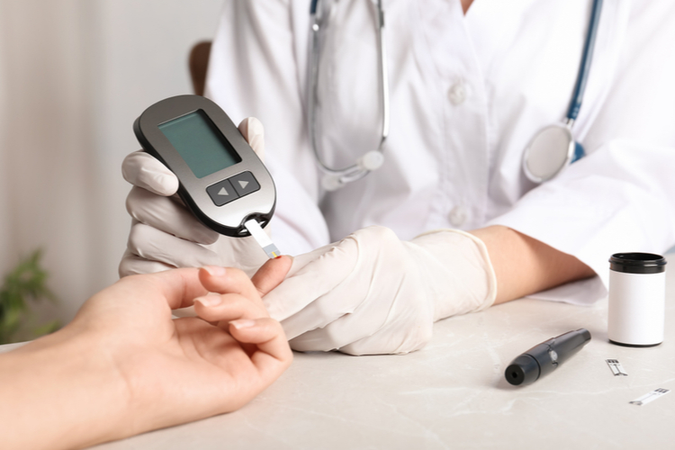 Doctor checking blood sugar level with glucometer at table. Diabetes test