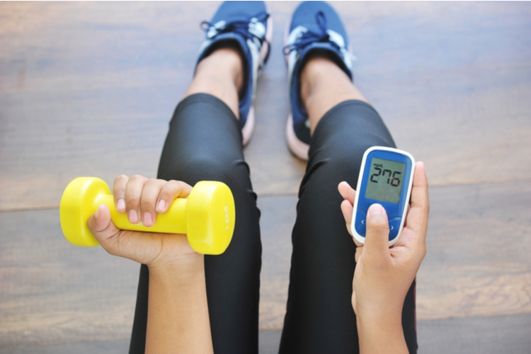 Girl holding dumbbell and glucose meter,concept for diabetes lifestyle and healthy.