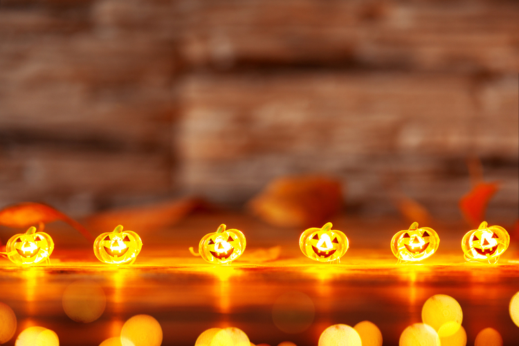 Garland of Glowing Halloween Pumpkins on Dark Wooden Background With Copy Space.