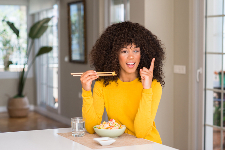 Woman practicing mindful eating instead of stress eating wearing yellow shirt.