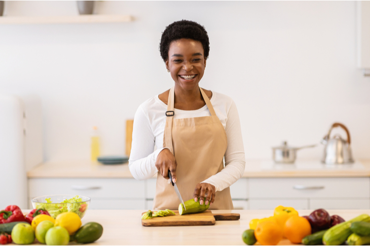 Woman cutting zucchini vegetable following a stuffed zucchini recipe.