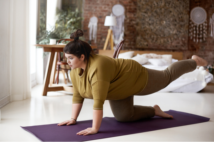 woman is exercising on mat, lifting one leg, trying to hold balance