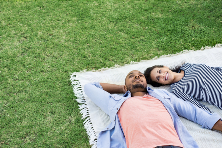 couple lying on blanket on grass