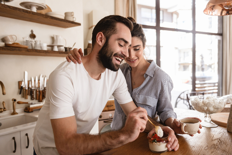 lovely brunette couple drinking coffee and eating desserts during breakfast in kitchen at home.