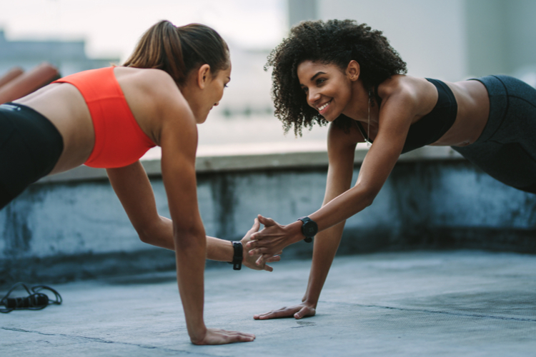 Fitness women doing push ups on rooftop facing each other. 