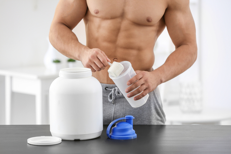 Young sporty man preparing protein shake at table