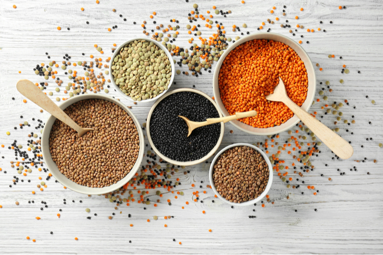 Bowls with different types of lentils on wooden table