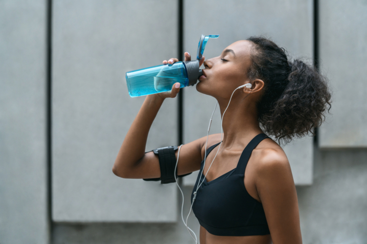 Fitness woman drinking water from a bottle after workout