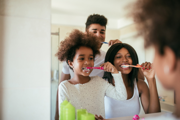 happy afro-american family washing their teeth during daily morning routine.
