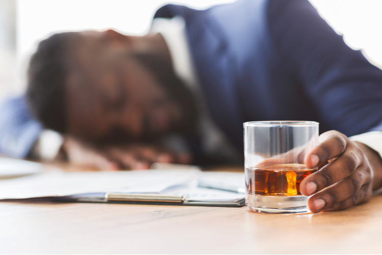 Drunk african employee holding glass of beer