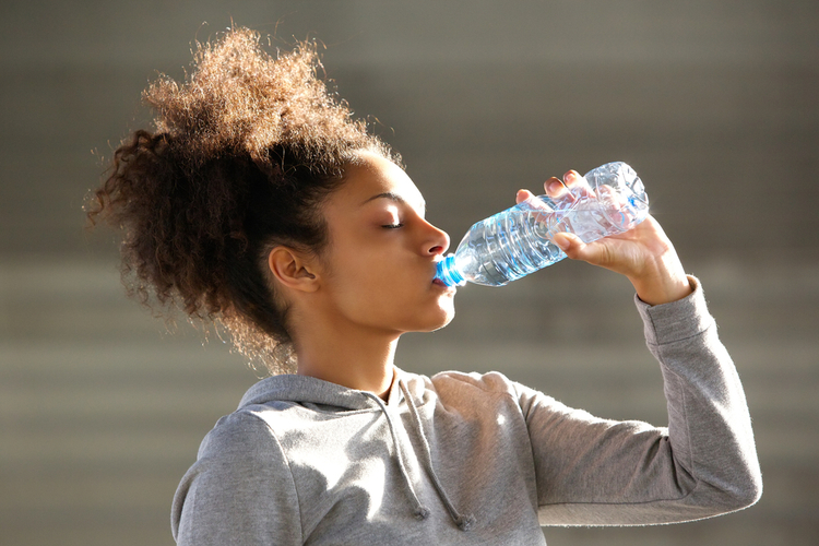 Young woman drinking water from bottle.