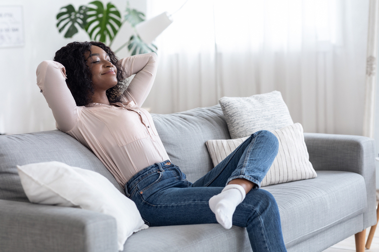 Woman Leaning Back On Couch With Closed Eyes.