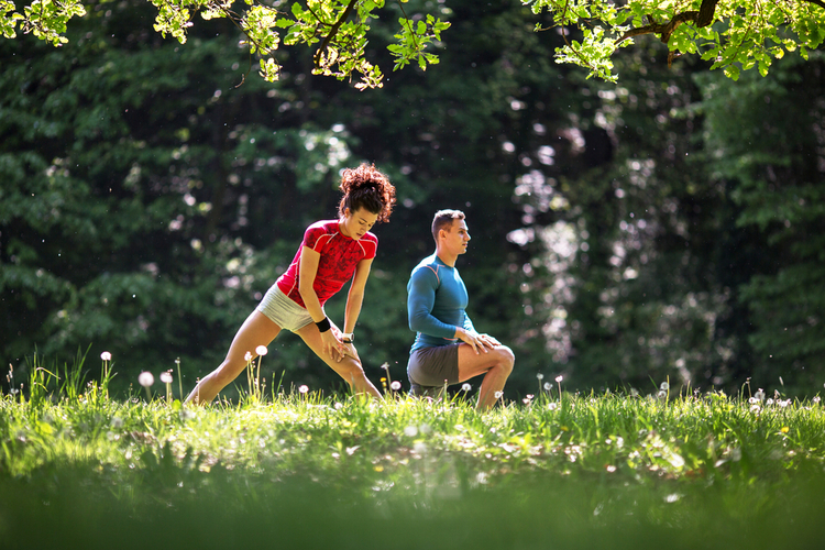 Young couple stretching and relaxing after jogging outdoor.
