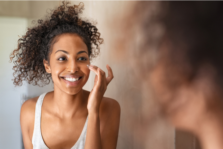 Young black woman applying moisturizing cream