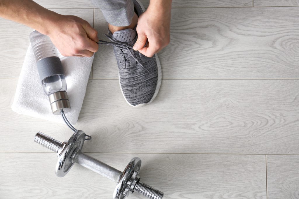 water bottle, towel and weight next to a man tying his shoe