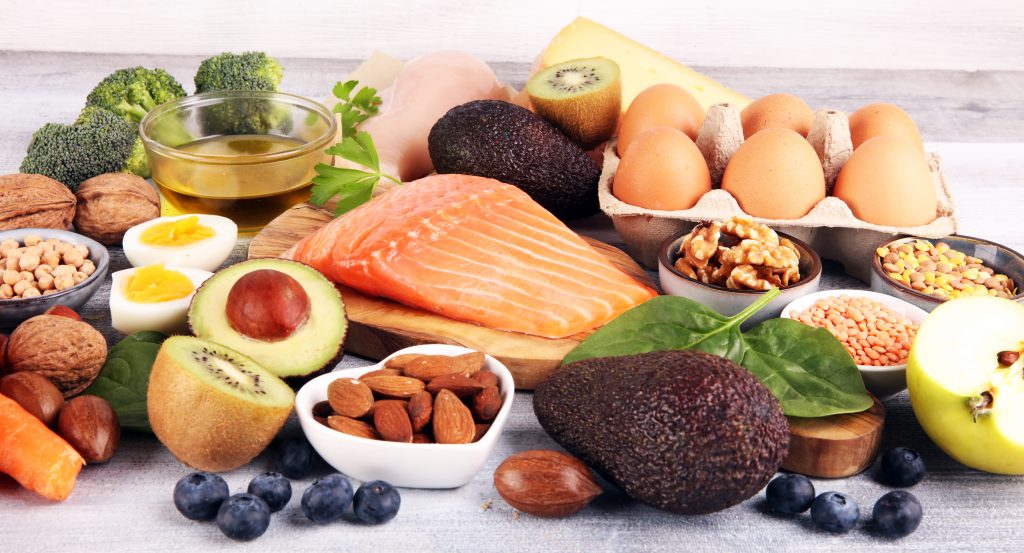 picture of healthy foods such as salmon, avocado, greens, and eggs