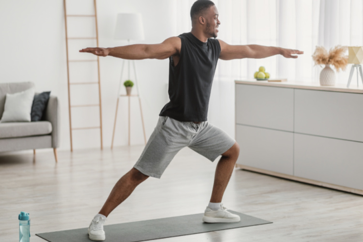Man Doing Yoga Standing In Warrior Pose At Home.