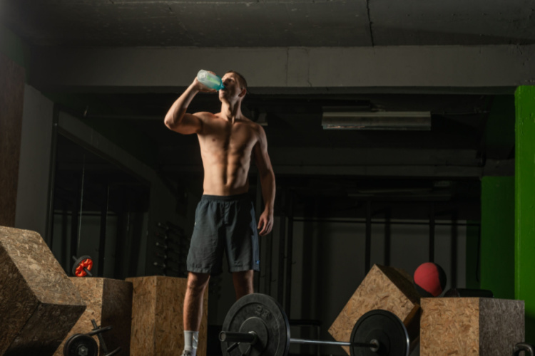 Muscular man taking a break from a hardcore workout while drinking