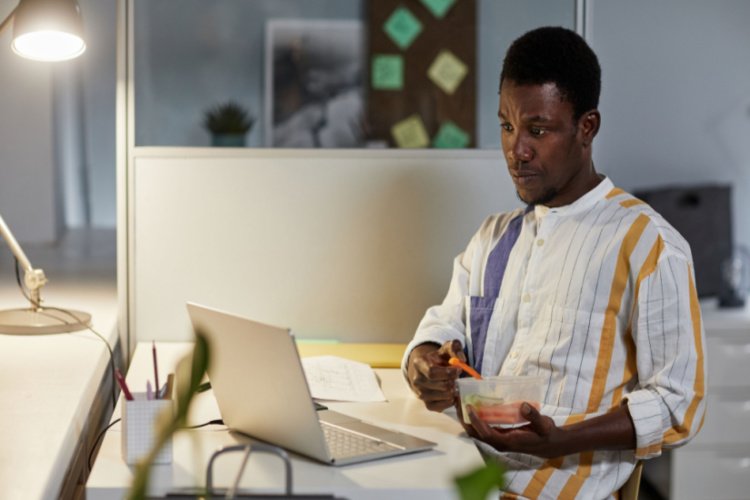 man eating healthy snack while working