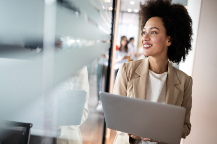 businesswoman smiling while standing by windows in office