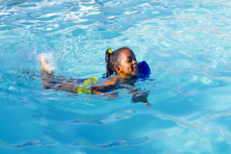 Girl swims with one water wing in the pool