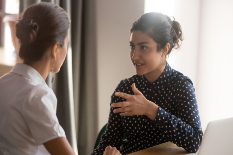 mentor teacher worker talk to female colleague teach intern discussing new skills learning sit