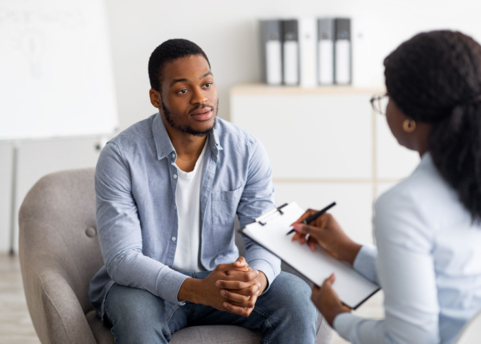 black man having session with professional psychologist at mental health clinic.