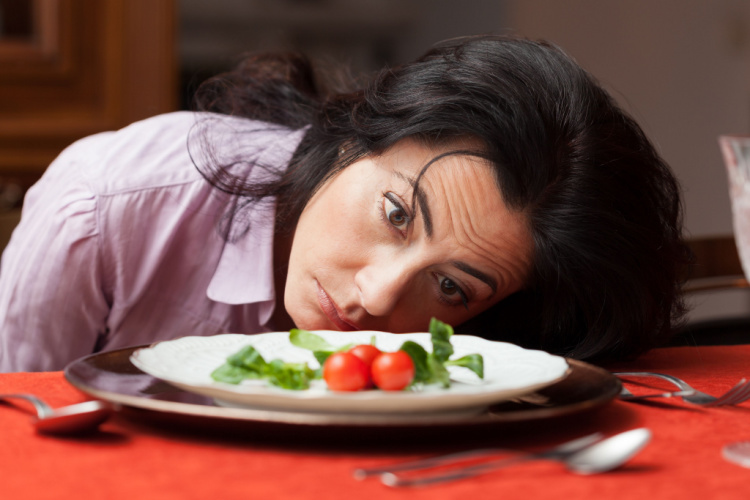 Woman looking to a little salad is tired about diet.