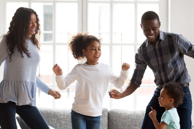 Happy family of four have fun together in living room.