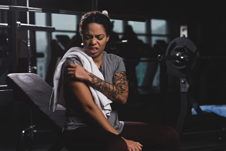 Woman with tattoo touching hand while suffering from pain